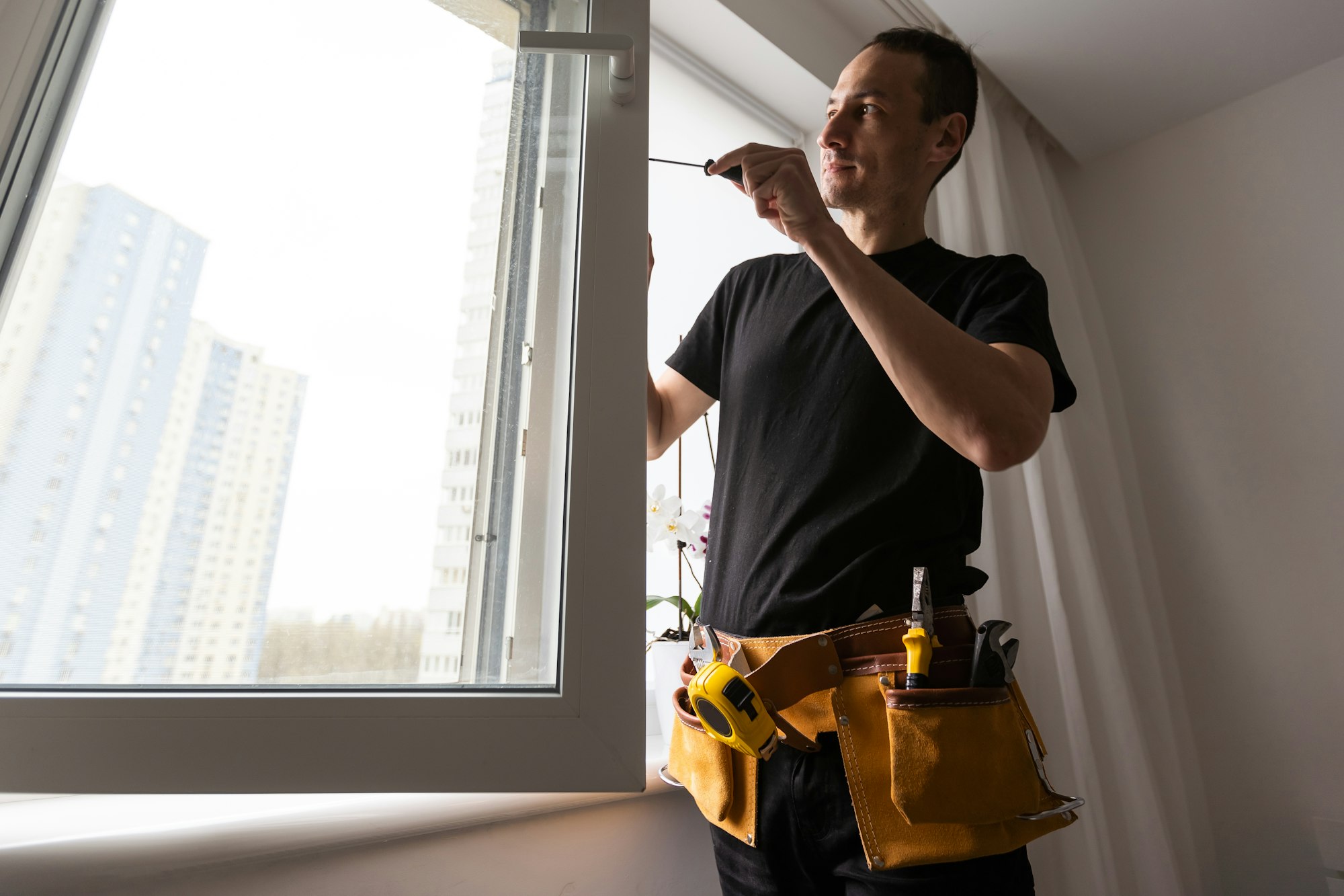 Techniker justiert den seitlichen Beschlag eines geöffneten Kunststofffensters